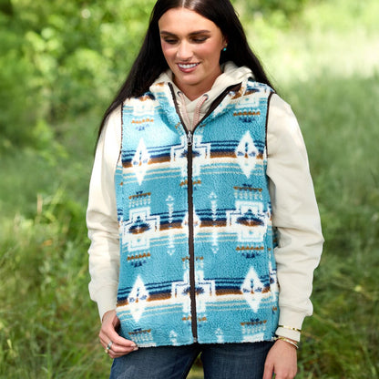 Woman wearing a blue patterned vest outdoors in a grassy area