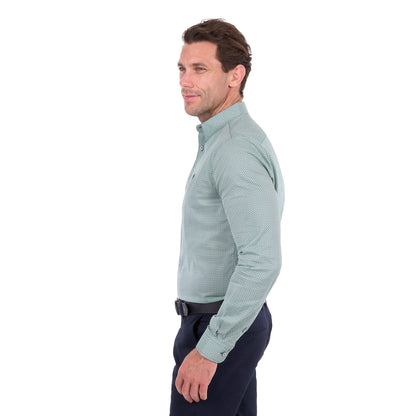 A man shown in profile wearing a light sage green long-sleeve button-down shirt with a subtle micro-pattern, paired with dark navy trousers, against a plain white background.