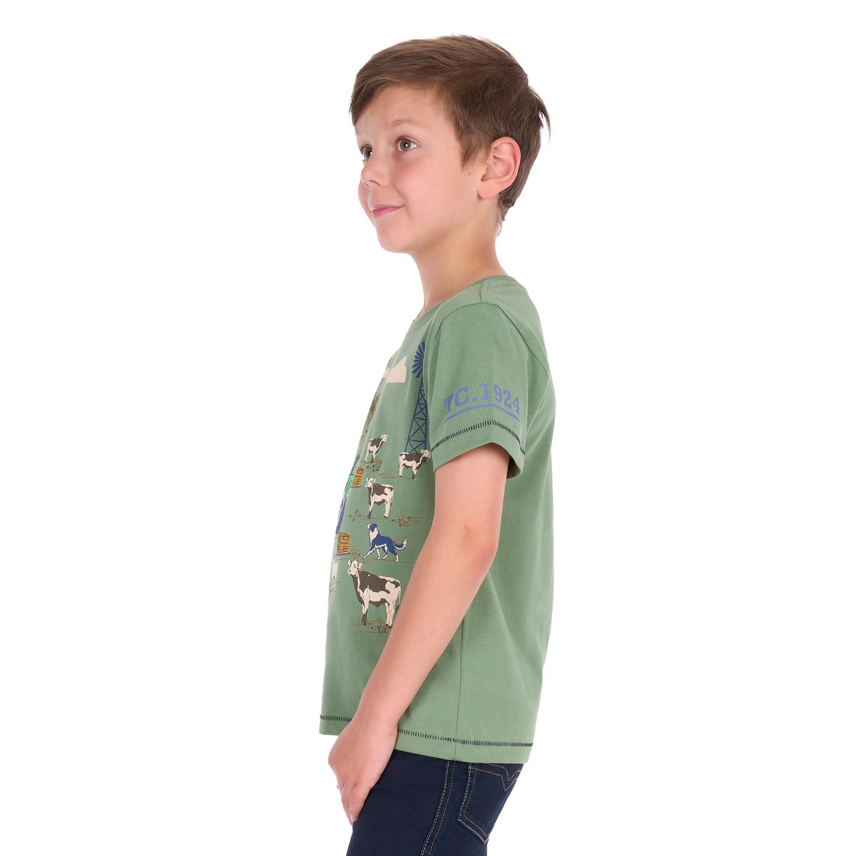 A young boy wearing a sage green short-sleeve t-shirt with a cow graphic print, shown in profile against a white background.